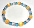 Gold-colored oval cat-eye bracelet with blue faceted beads and clear barrel-shaped accents.